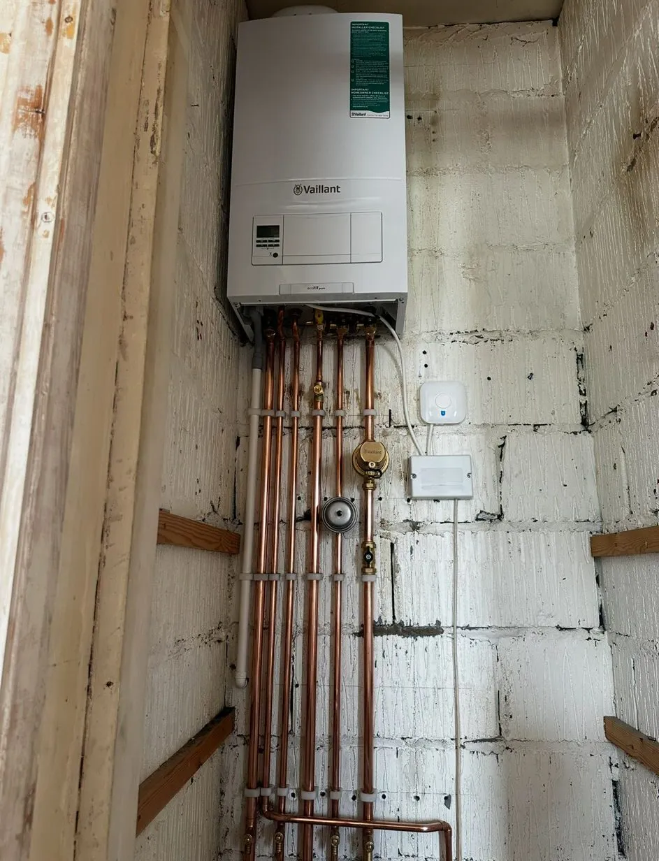 Vaillant boiler fitted to a block wall above a run of new copper pipes and isolation valves
