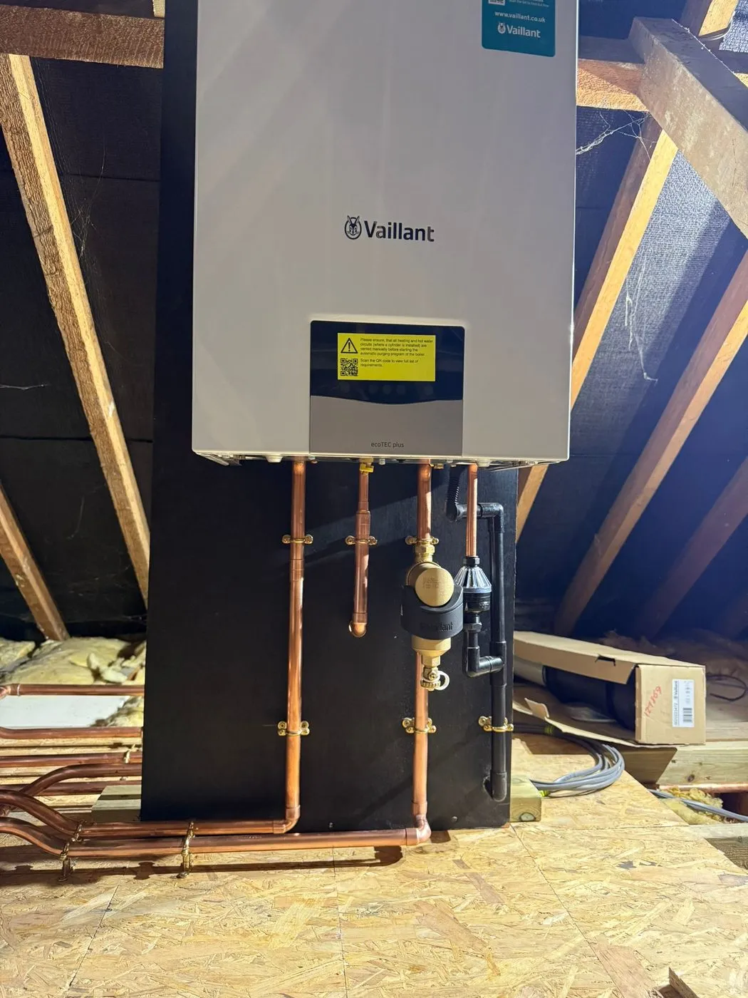 Wall-mounted Vaillant boiler installed in a loft, with new copper pipework running down to a boarded floor
